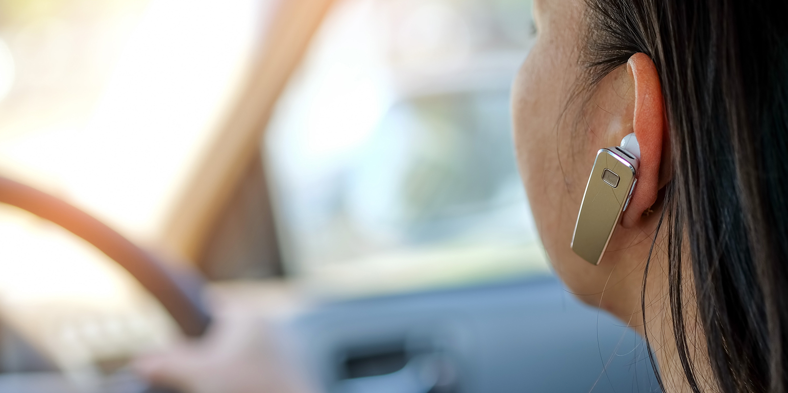 Woman wearing a hands free device in her ear whilst driving